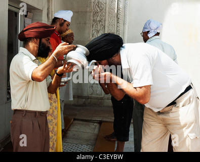 Mann, die Zuführung von Wasser mit einem anderen Mann bei einem Gurudwara, Gurdwara Bangla Sahib, New Delhi, Indien Stockfoto