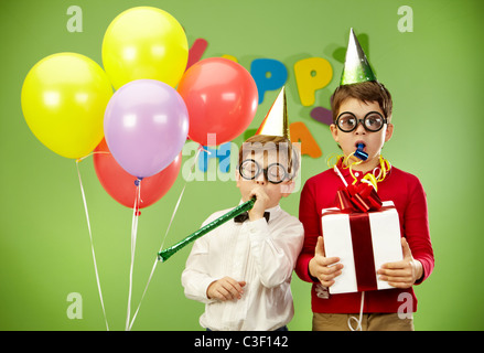 Porträt von intelligenten jungen in lustige Brillen hineinblasen kindisch Spielzeug Stockfoto