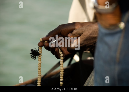 Ein Muslim zählen seine Gebetskette auf der Fähre von Banjul nach Barra Gambia Stockfoto