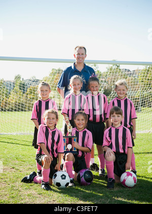 Coach und Mädchen-Fußball-Spieler posiert mit Trophäe Stockfoto