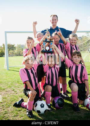 Coach und Mädchen-Fußball-Spieler posiert mit Trophäe Stockfoto