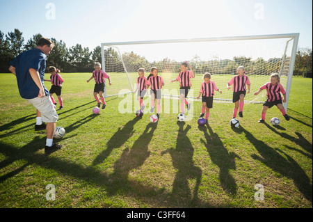 Trainer üben mit Mädchen-Fußball-Spieler Stockfoto