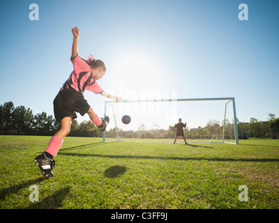Mädchen-Fußball-Spieler treten Fußball am Netz Stockfoto
