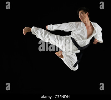 Asiatischen männlichen Karate Schwarzgurt treten in Luft Stockfoto
