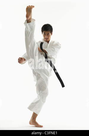 Asiatischen männlichen Karate Schwarzgurt treten in Luft Stockfoto