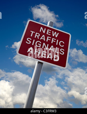 Neue Verkehrszeichen voraus unterzeichnen in England. Schneiden Sie vor einem blauen Himmel mit weißen Wolken. Stockfoto