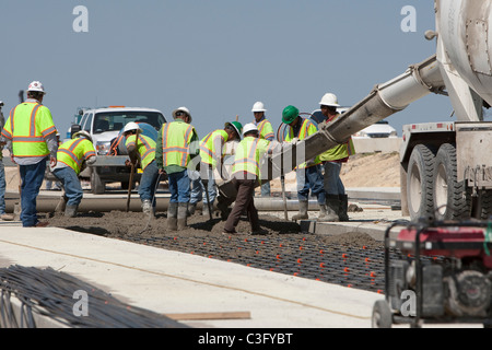 Team von männlichen Autobahn Bauarbeiter Gießen Frischbeton auf Strahl Raster für die Strecke der Autobahn Neubau in Texas Stockfoto