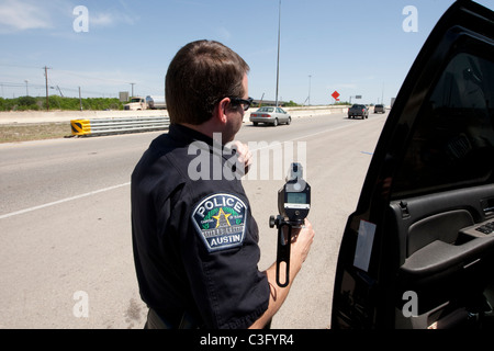 Männlicher Polizist benutzt Radar Geschwindigkeit Waffe, um Geschwindigkeitsüberschreitungen fangen Fahrer auf der Autobahn in Austin Texas USA Stockfoto