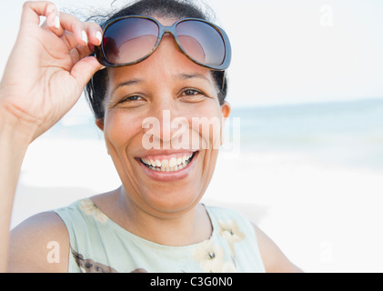 Lächelnde schwarze Frau mit Sonnenbrille am Strand Stockfoto