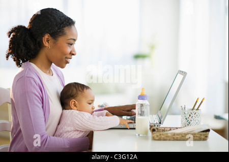 Gemischte Rassen Frau hält Baby und mit laptop Stockfoto