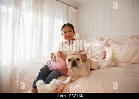 Asiatische Mädchen sitzt auf dem Bett mit Hund Stockfoto