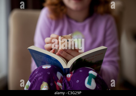 Kaukasische Mädchen sitzend mit Buch und Haustier hamster Stockfoto