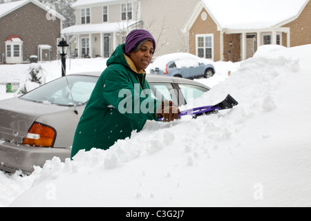 Afroamerikanische Frau Schnee von der Windschutzscheibe kratzen Stockfoto