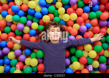 bunte Kugeln lustig park kleine Mädchen liegend gestikulieren glücklich Stockfoto