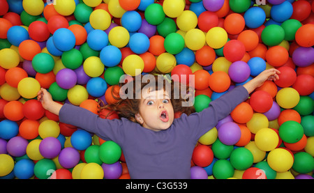 bunte Kugeln lustig park kleine Mädchen liegend gestikulieren glücklich Stockfoto