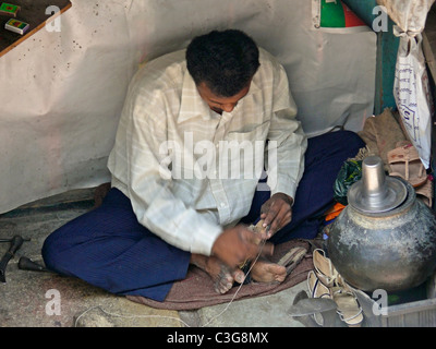 Eine Kaste, Schuster, reparieren Schuhe am Straßenrand, Indien Stockfoto