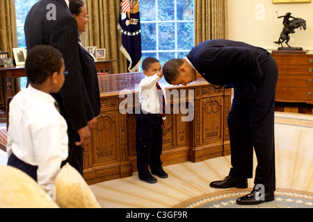 Präsident Barack Obama beugt sich über, so dass der Sohn des weißen Hauses Bediensteten den Kopf bei einem Familienbesuch zum Oval klopfen können Stockfoto