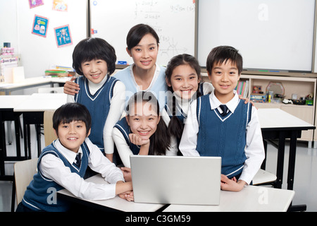 Schüler und Lehrer versammelten sich um einen Computer im Klassenzimmer Stockfoto