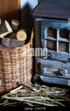 Kaminofen und einen Korb von Protokollen in einem Landhaus. Großbritannien Stockfoto