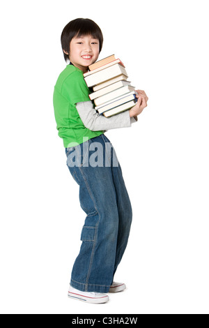 Jungen tragen einen großen Stapel Bücher Stockfoto