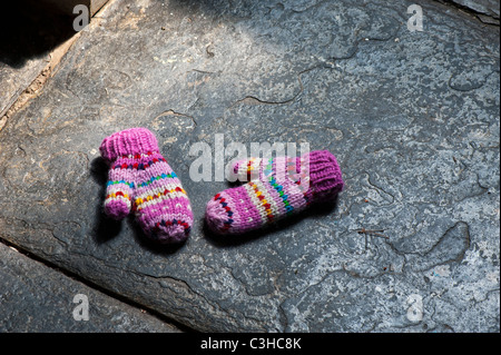 Young Girls bunt gestreifte Handschuhe auf einem Schieferboden Stockfoto