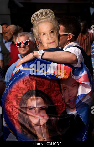 Menschen tragen die Maske der Königin Elisabeth und eine Fahne von Prinz William und Kate feiern Sie ihre Hochzeit, Soho, London. Stockfoto