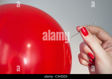 Nahaufnahme von roten Ballon und Frau die Hand, die Nadel Stockfoto
