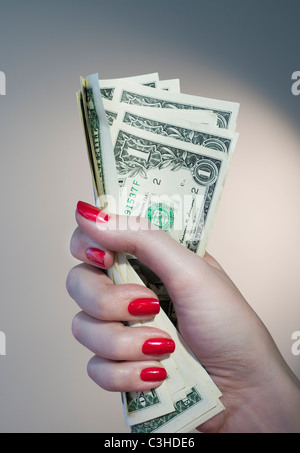 Nahaufnahme von Frauenhand mit rotem Nagellack hält Bündel Dollar-Banknoten Stockfoto