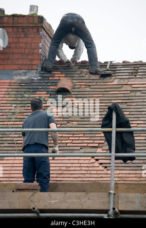 Mann auf dem Dach des Hauses neben Schornstein Abstreifen der alte Fliesen, Re Überdachung Wohn-Hause Ontop Bedachungen, Sheffield, England Stockfoto