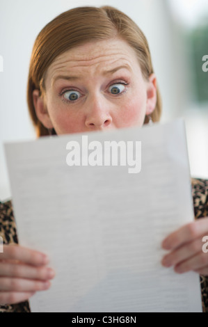 Frau liest Dokumente Aussehen überrascht Stockfoto