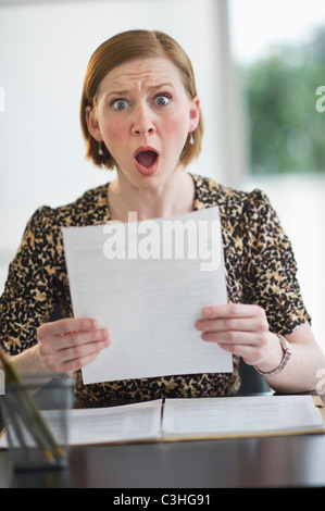 Frau liest Dokumente Aussehen überrascht Stockfoto