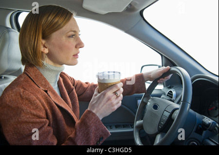 Frau Auto fahren und Kaffee trinken Stockfoto