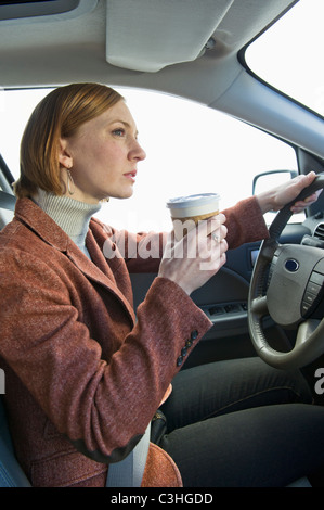 Frau Auto fahren und Kaffee trinken Stockfoto