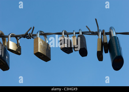 Vorhängeschlösser mit Herzform befestigt Drahtzaun mit blauem Himmelshintergrund Stockfoto