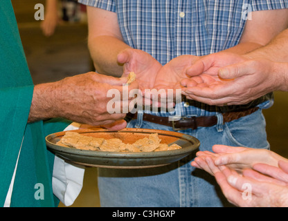 Alle sind herzlich willkommen am Tisch des Herrn, wie die konsekrierte Hostie befindet sich in offene Hände auf Mass. Stockfoto