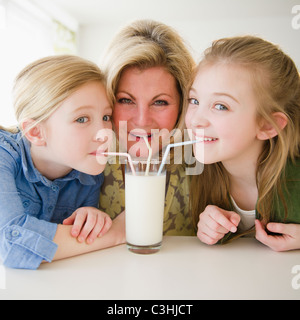 Mutter und Töchter (8-11) trinken Milch durch Strohhalme Stockfoto