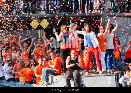 Königstag, der Geburtstag des Königs, ehemals Königinnentag. Amsterdam Canal Parade Boote Menschen feiern schießen orangefarbene Konfetti. Stockfoto