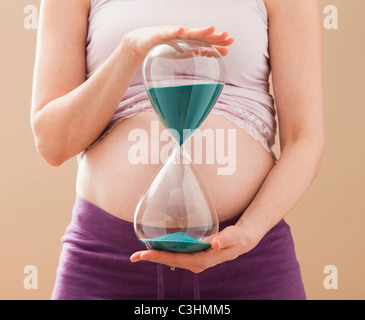 Junge schwangere Frau Holding Sanduhr Stockfoto