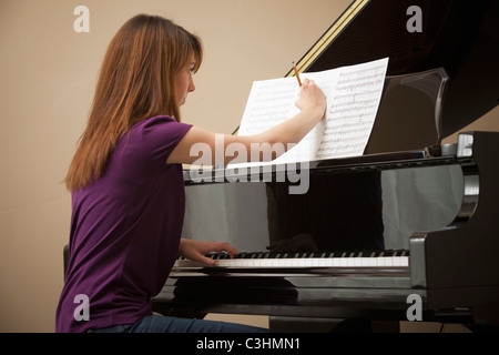 Junge Frau, die Kennzeichnung Partitur vor Einstellung Grand Piano spielen Stockfoto