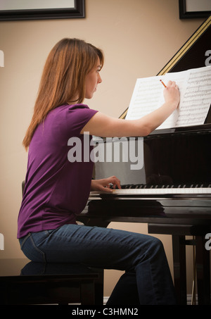 Junge Frau, die Kennzeichnung Partitur vor Einstellung Grand Piano spielen Stockfoto