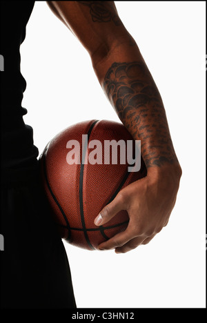 Mittelteil der tätowierte Mann hooding basketball Stockfoto