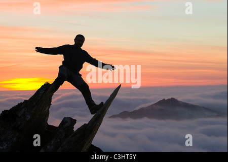 Harter fiel über den Wolken auf nassen Seitenkante im Lake District und eine Silhouette Kletterer. Stockfoto