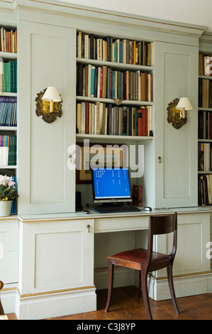Laptop auf Platz auf dem Schreibtisch im Alkoven unter offenes Buch-Regal Stockfoto