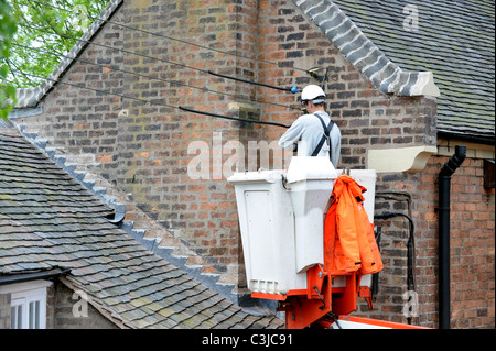 Elektrische Conractor Repalcing alte externe Kabel auf alten Haus UK Stockfoto