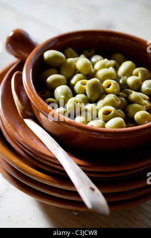Oliven in einem Terrakotta-Topf auf einem Stapel auf Terrakotta-Platten Stockfoto