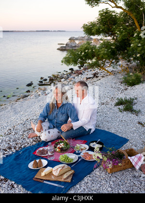 Älteres Paar mit Picknick am Strand Stockfoto