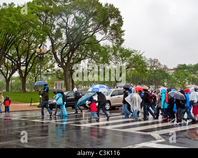 Mit Regenjacken und Schirme, folgen Sie Touristen eine Anleitung an einem regnerischen Tag auf der National Mall in Washington, D.C. Stockfoto