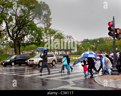 Mit Regenjacken und Schirme, folgen Sie Touristen eine Anleitung an einem regnerischen Tag auf der National Mall in Washington, D.C. Stockfoto