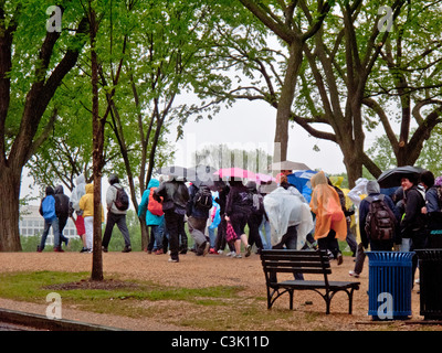 Mit Regenjacken und Schirme, folgen Sie Touristen eine Anleitung an einem regnerischen Tag auf der National Mall in Washington, D.C. Stockfoto