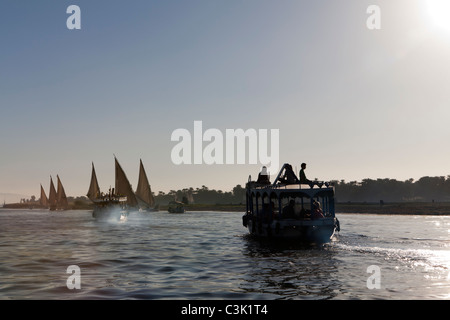 Im Anschluss an eine Nilwasser Wasser Taxi und mehrere Feluken Überschrift in den Sonnenuntergang auf den glitzernden Fluss, Ägypten, Afrika Stockfoto